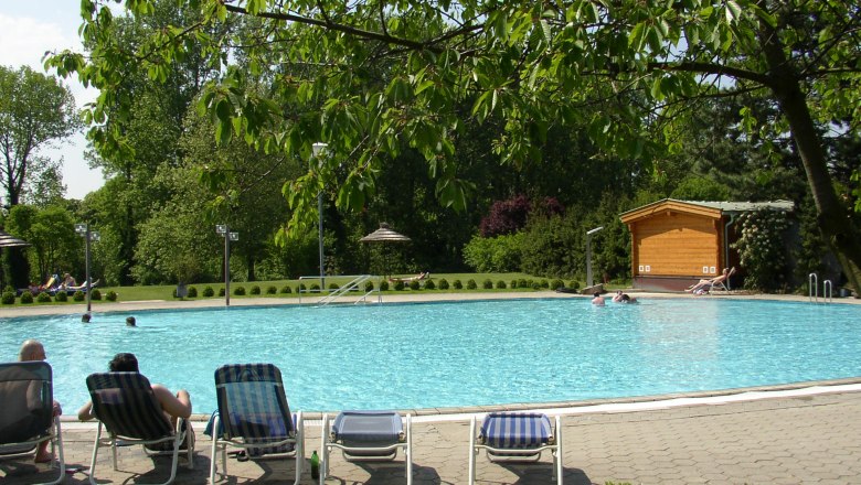 Freibad mit Liegestühlen, umgeben von Bäumen und grüner Landschaft., © Donau Niederösterreich